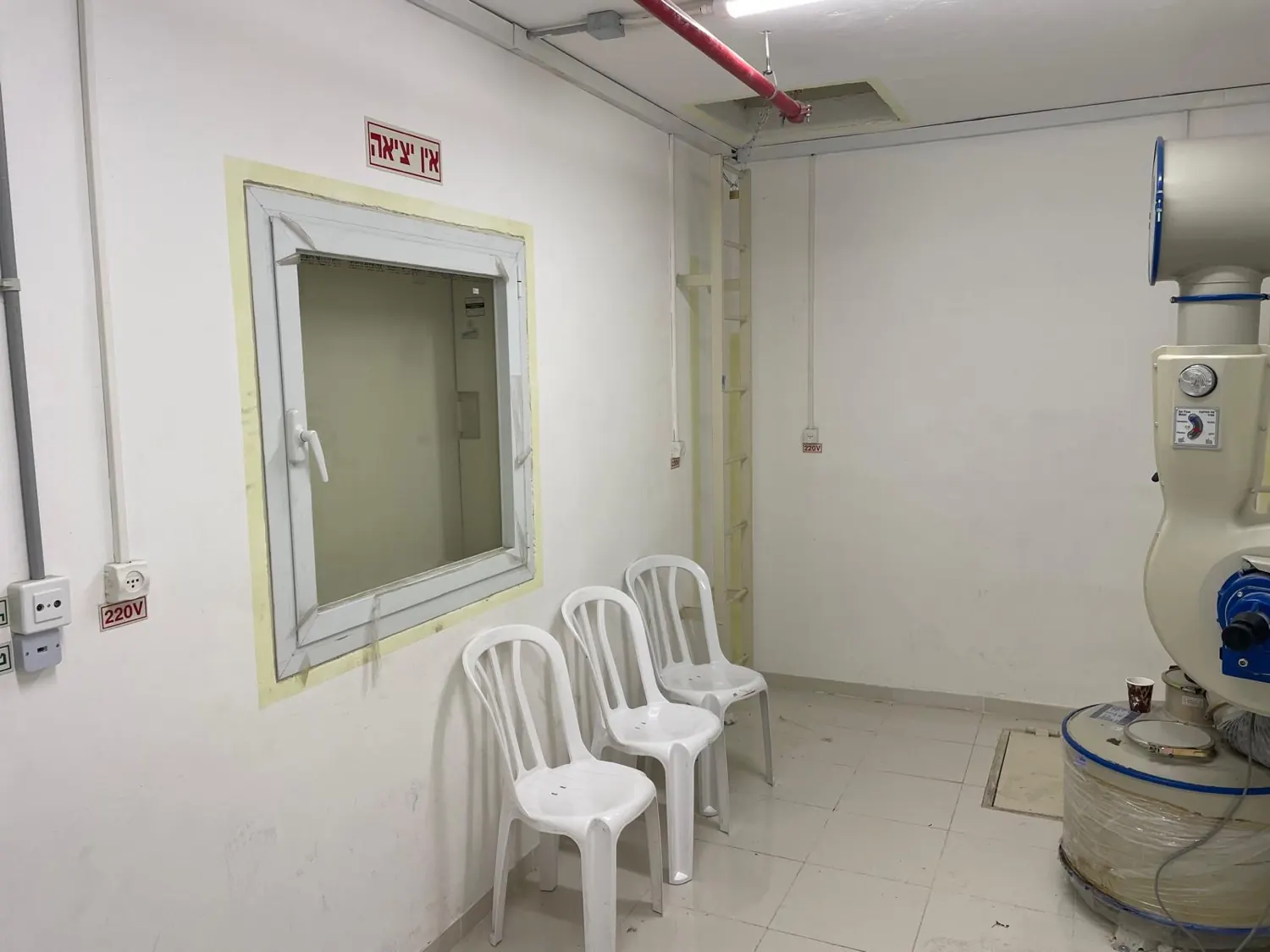 החיים הם תקופה קשה · חדר לבן ריק: חלון, כסאות פלסטיק, יחידת סינון, שלט 'אין יציאה' וסולם